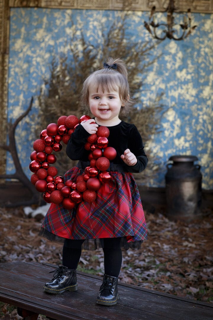 little girl with red ball wreath