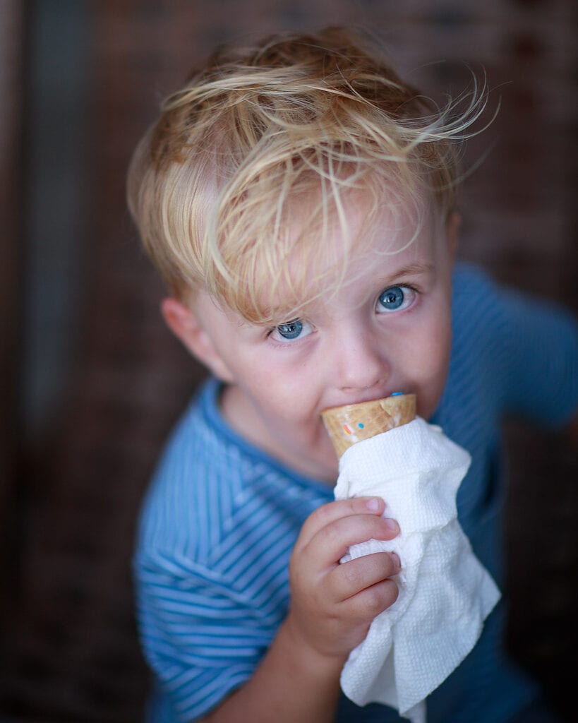 Blue eyed boy eating ice cream cone