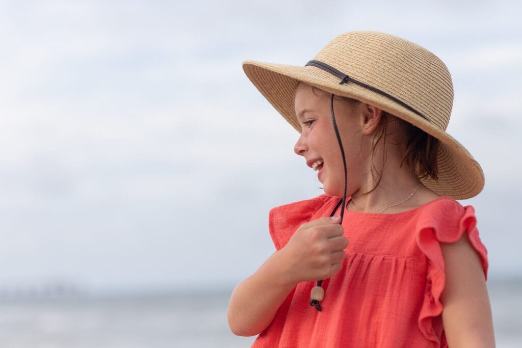 Girl laughing with hat on beach