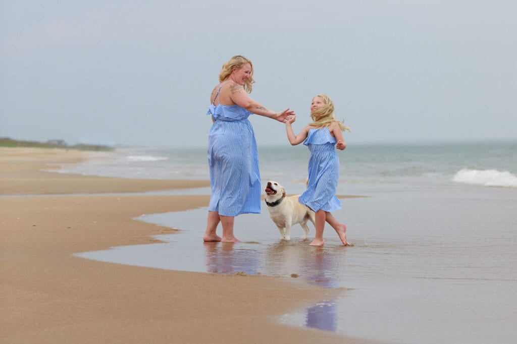 mother and daughter with dog enjoy the evening on the beach sanderling nc