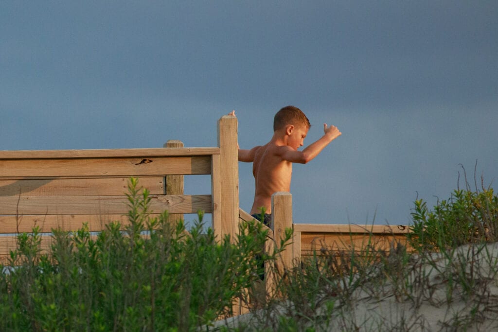 Boy running off the beach on walkway, Corolla NC