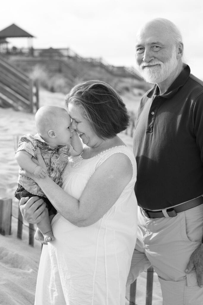 grandmother and grandfather on beach with baby boy