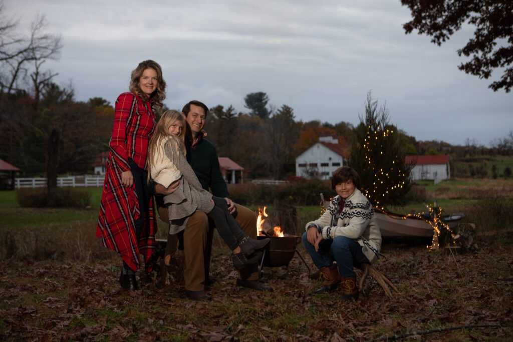 Family at dusk in rustic setting with camp fire