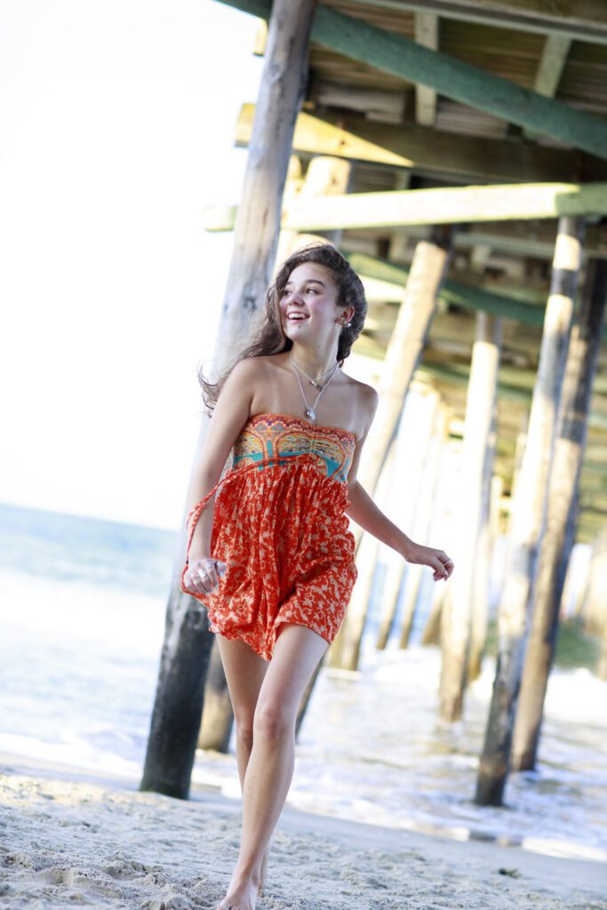 Senior photo OBX girl running under pier