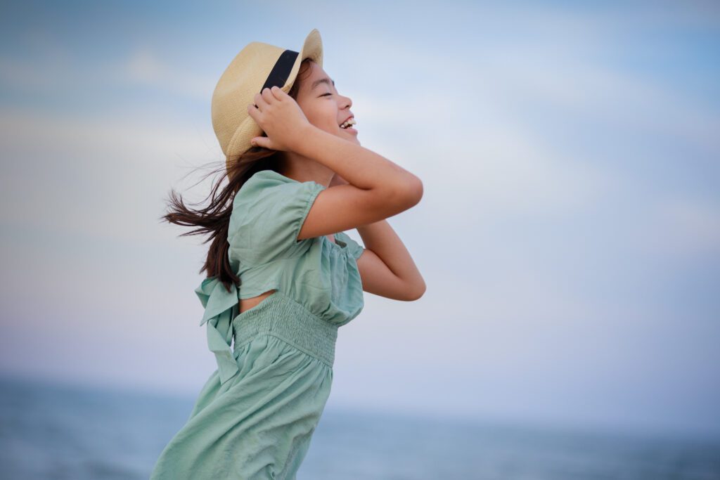 Girl with hat loving the beach in the evening Duck NC