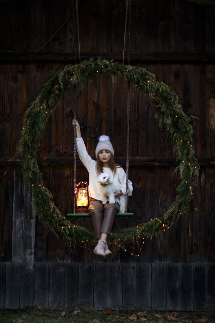 Little girl and her dog on wreath swing hangin on old barn in Leesburg Virginia