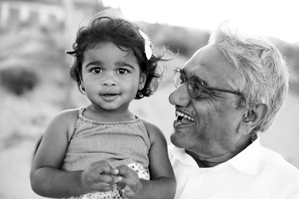 grandfather holding his granddaughter on the each in a family portrait sessions in Duck NC