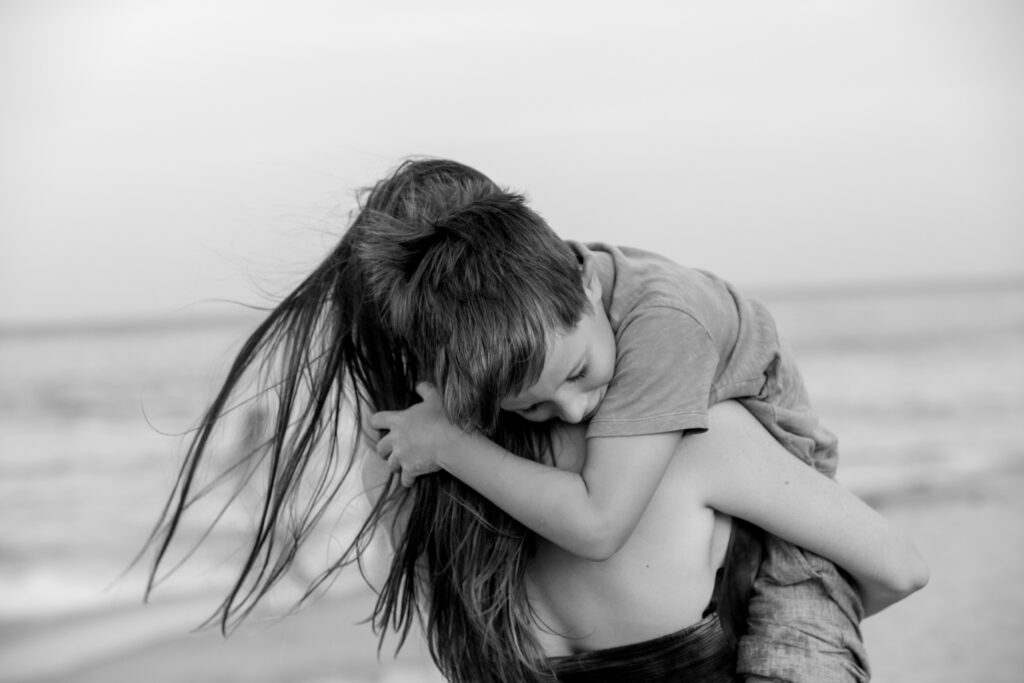 moody black and white image on beach of a boy and his mom, duck NC