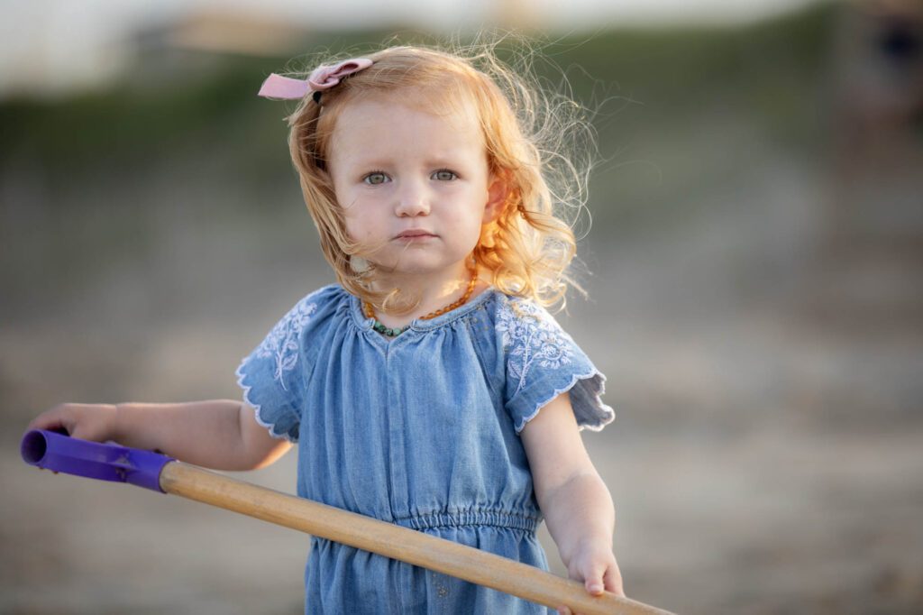 Little red haired girl making sandcastle on the beach with the golden sunlight, in Duck, NC