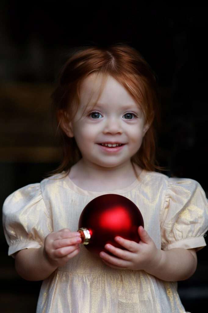 little girl with large red Christmas ball