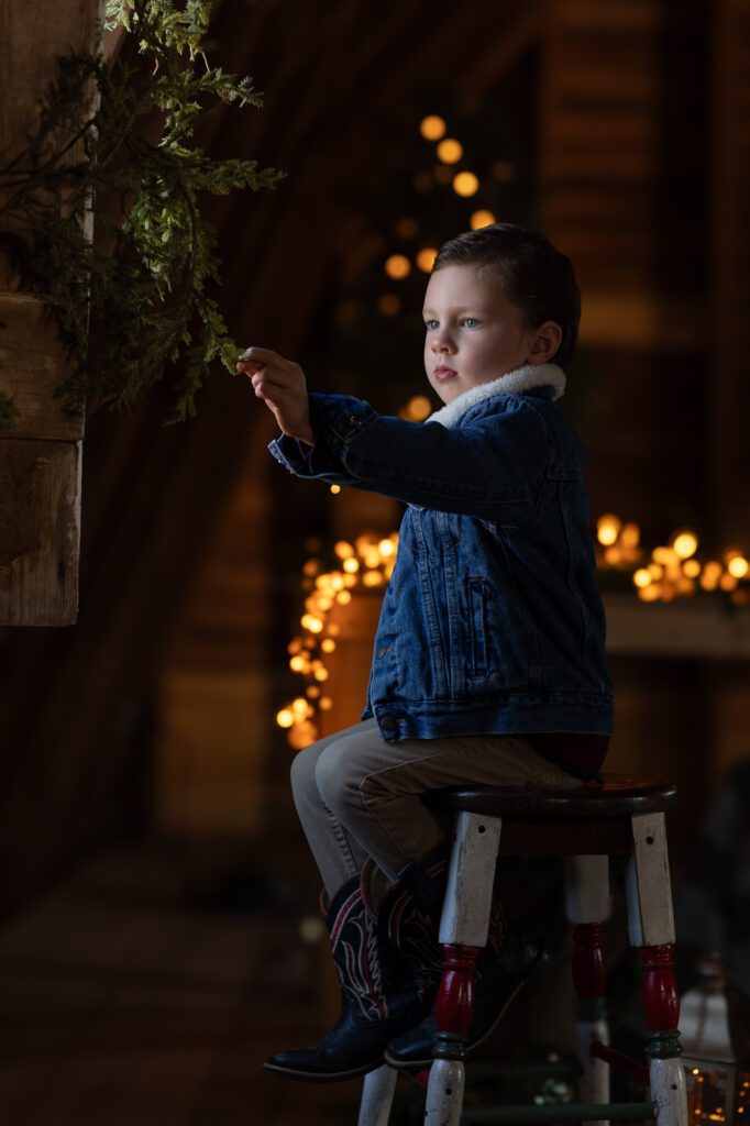 Little boy in old barn with holiday lights
