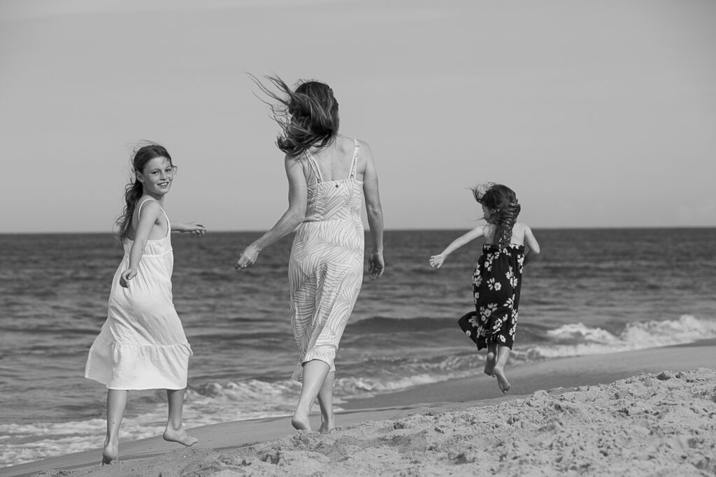 Mom and daughters on the beach dancing at sunset