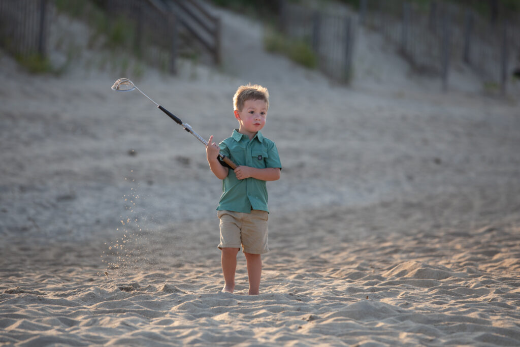 little boy collecting sand at sunset on the beach in Duck, nc