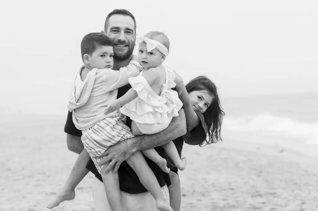 Dad holding his three small children on the beach, in Black and White