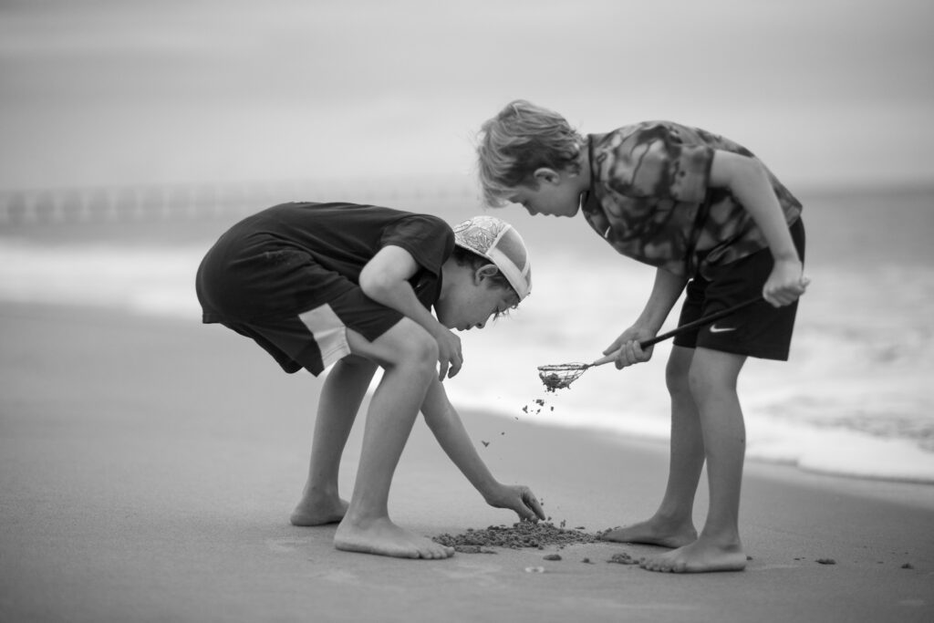 Two boys on the beach searching for crabs to use as bait, Duck, NC