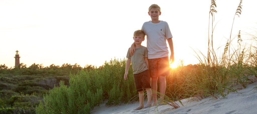 Brothers on the dunes at sunset in Corolla, NC