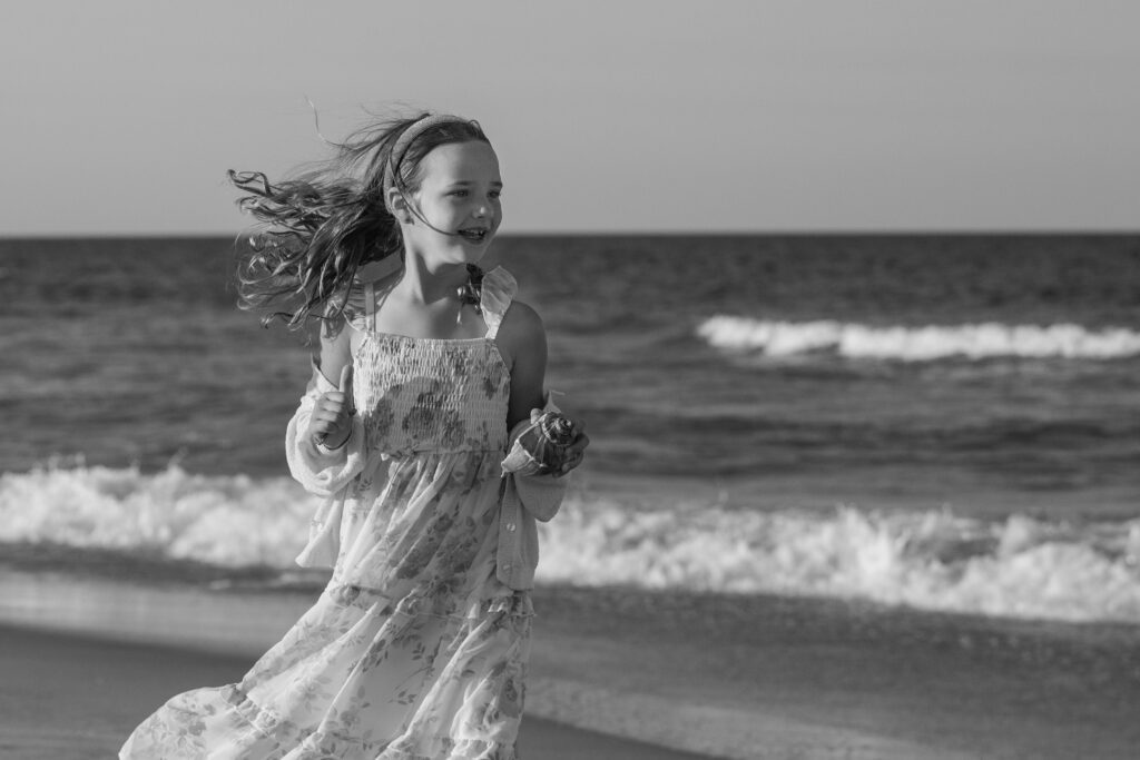 Girl running on the beach with whelk shell