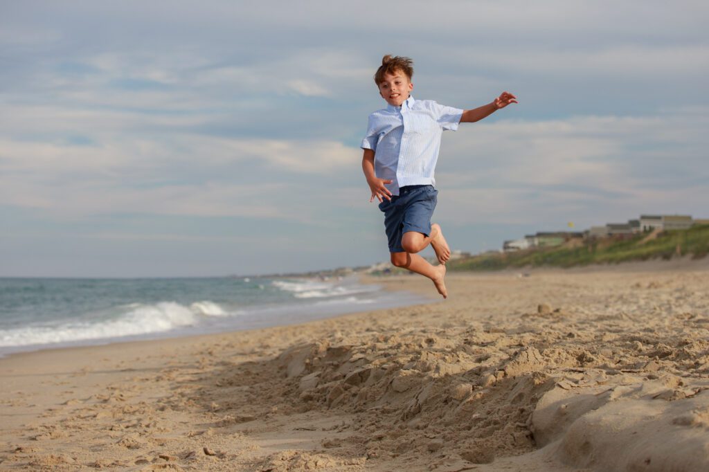 boy jumping in the air on the beach in Duck, NC