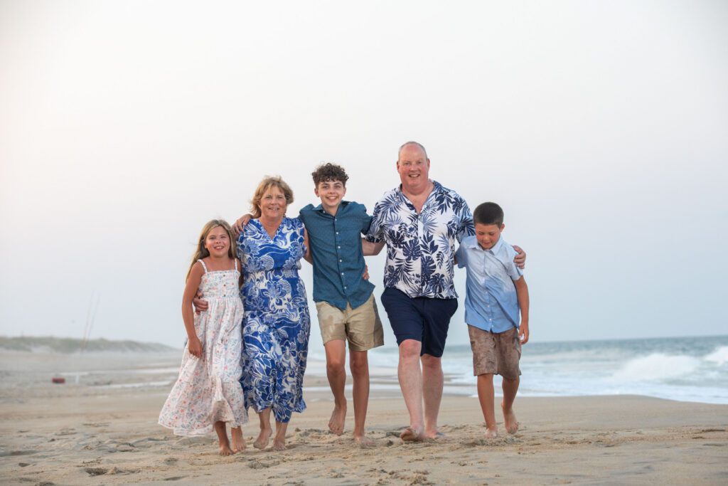 Grandparents running along the beach in Hatteras, NC with their grandchildren