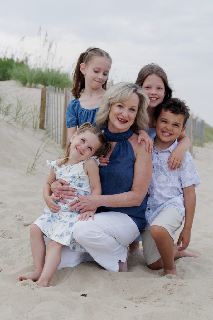 Grandmother on the beach embraced with all of her small grandchildren